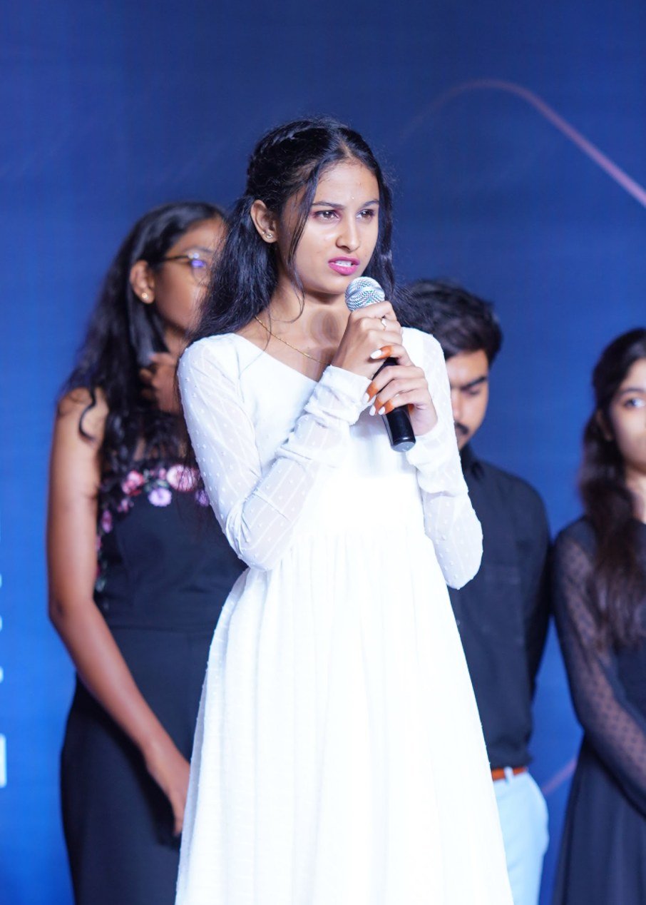 Nikhila speaking on stage at an award ceremony