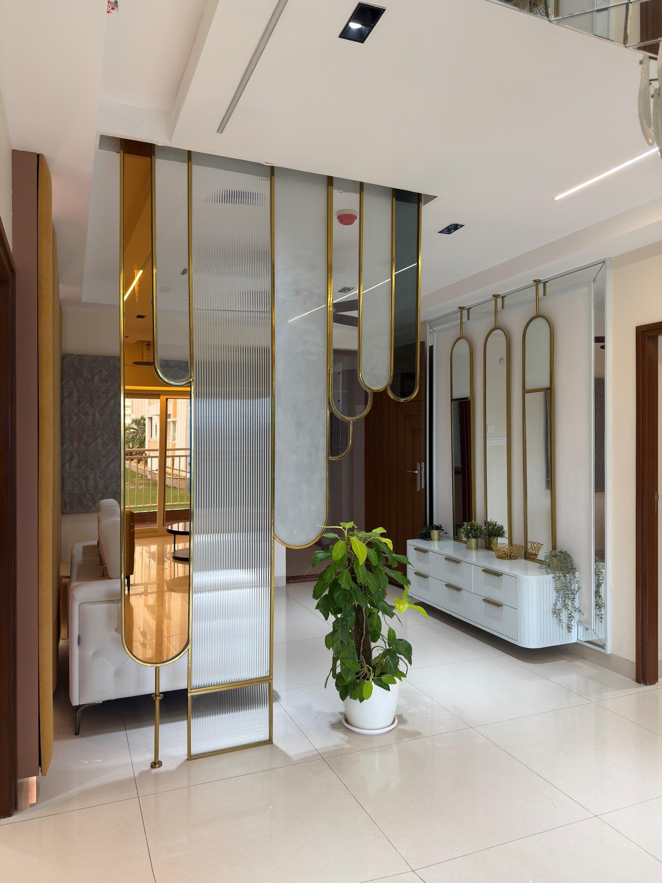 Brass-framed mirrored partition and fluted console in a bright entrance hall, designed by Nikhila